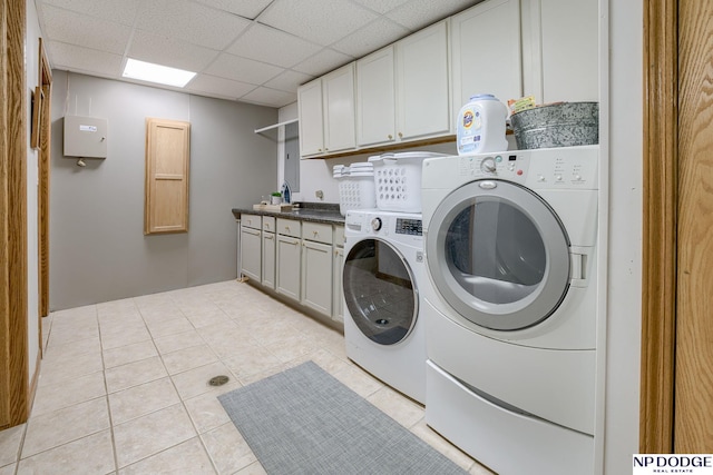 clothes washing area with light tile patterned floors, cabinet space, and washer and clothes dryer