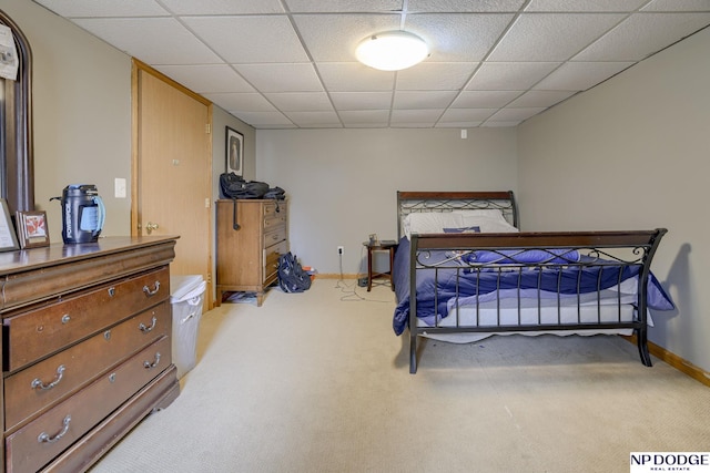 bedroom featuring light colored carpet, baseboards, and a paneled ceiling