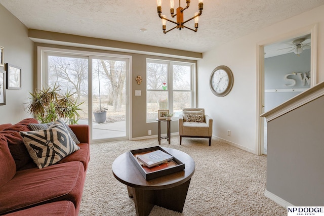 living room with ceiling fan with notable chandelier, baseboards, carpet floors, and a textured ceiling