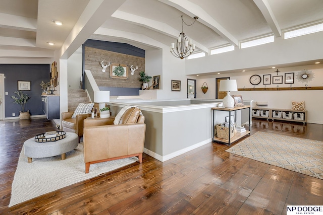 living area with beam ceiling, a chandelier, baseboards, and hardwood / wood-style flooring