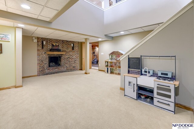 rec room featuring baseboards, a drop ceiling, carpet floors, recessed lighting, and a fireplace