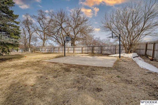 view of yard with basketball hoop and fence