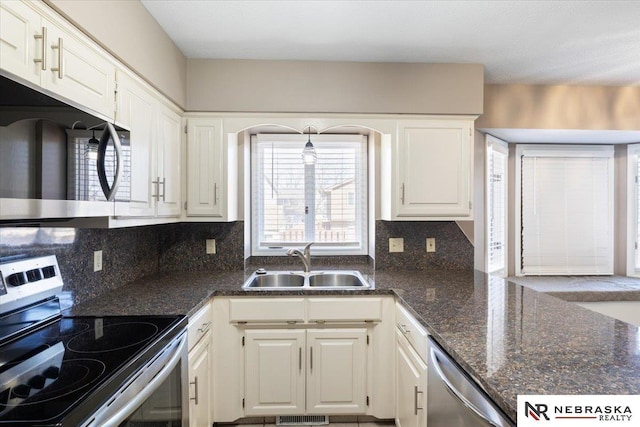 kitchen featuring decorative backsplash, white cabinets, appliances with stainless steel finishes, and a sink