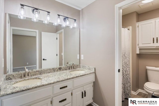 full bath with double vanity, toilet, baseboards, and a sink