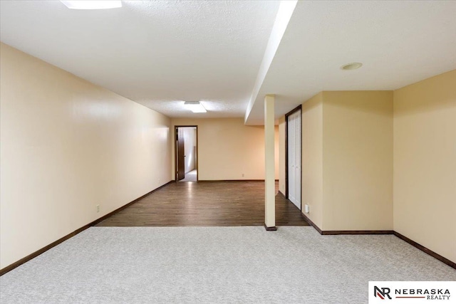 carpeted spare room featuring a textured ceiling and baseboards