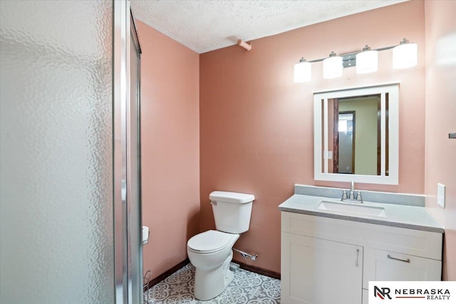 bathroom featuring vanity, baseboards, a textured ceiling, toilet, and a shower with door