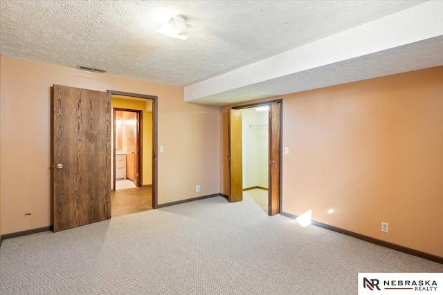 unfurnished bedroom with visible vents, baseboards, carpet, and a textured ceiling