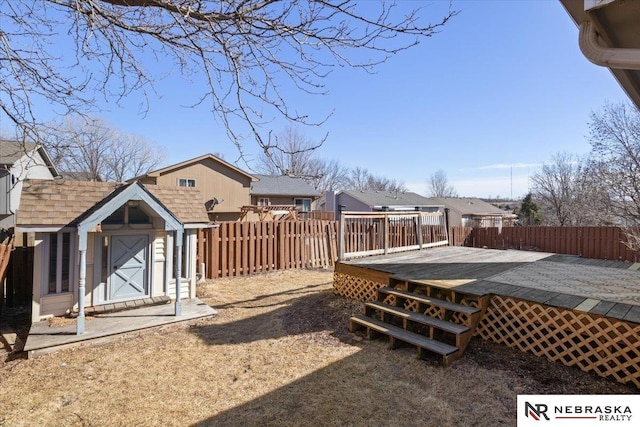 view of yard featuring a storage unit, a deck, an outbuilding, and a fenced backyard