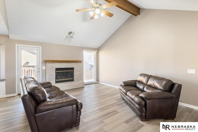 living area featuring beam ceiling, high vaulted ceiling, wood finished floors, baseboards, and a brick fireplace