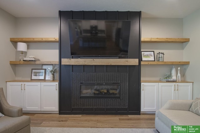 living area with a tiled fireplace and light wood finished floors