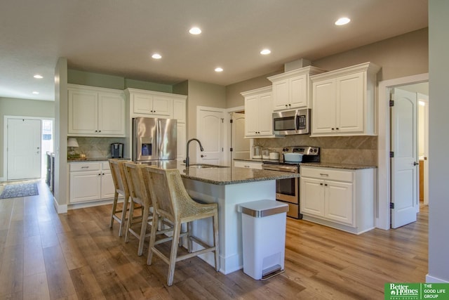 kitchen with a sink, light wood-style flooring, a breakfast bar, and stainless steel appliances