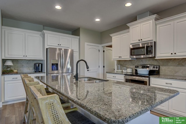 kitchen with a sink, white cabinets, dark wood-style flooring, and stainless steel appliances