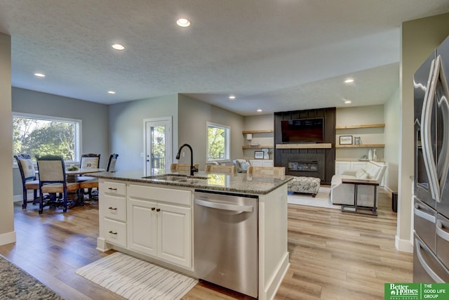 kitchen featuring light stone countertops, light wood-type flooring, appliances with stainless steel finishes, and a sink