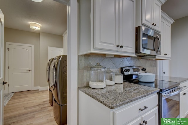 kitchen with backsplash, white cabinetry, stainless steel appliances, light wood finished floors, and washing machine and clothes dryer