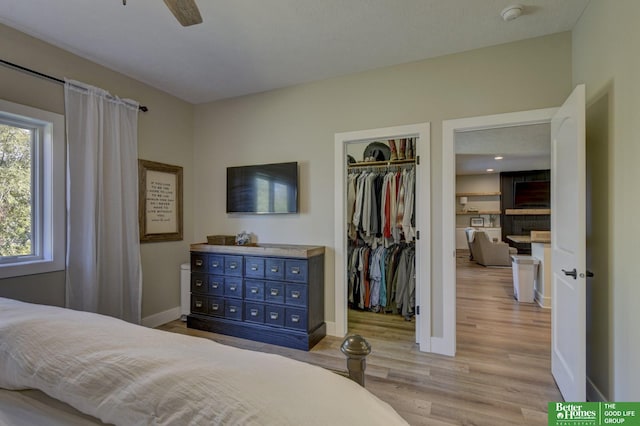 bedroom featuring light wood finished floors, a spacious closet, a closet, and baseboards