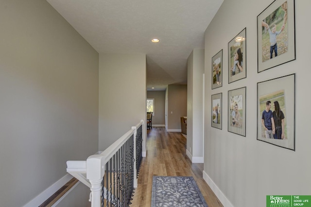 hall featuring recessed lighting, light wood-type flooring, an upstairs landing, and baseboards