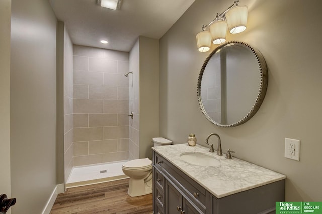 full bathroom with toilet, recessed lighting, tiled shower, wood finished floors, and vanity