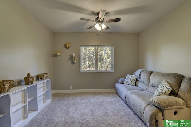 living room with a textured ceiling, light colored carpet, baseboards, and ceiling fan