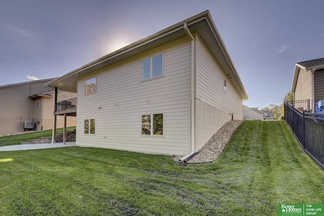 rear view of property featuring brick siding, a lawn, fence, and central AC