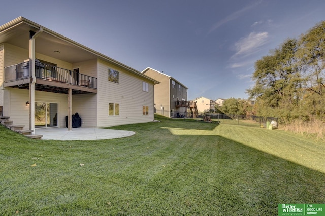 rear view of property featuring a balcony, a yard, a patio area, and fence