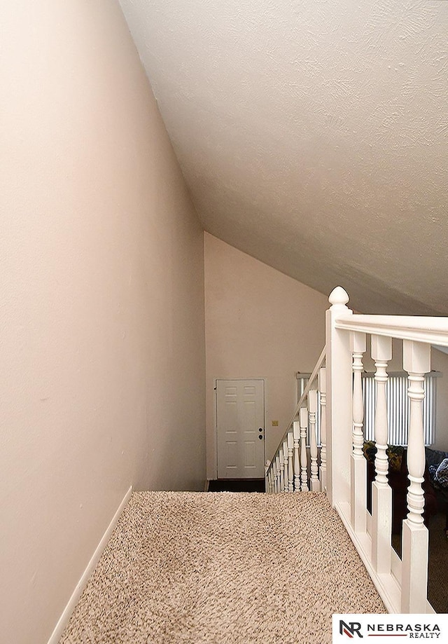 stairs with lofted ceiling, baseboards, carpet floors, and a textured ceiling