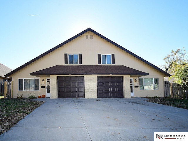 view of front of property featuring fence, driveway, roof with shingles, an attached garage, and brick siding