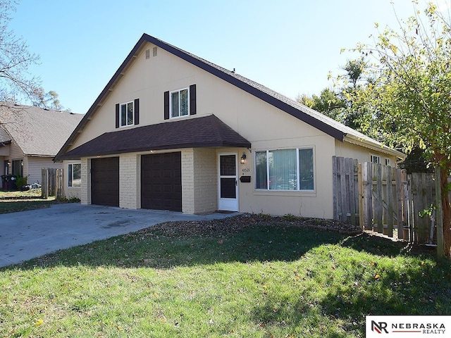 view of front of house featuring a front yard, fence, driveway, a garage, and brick siding