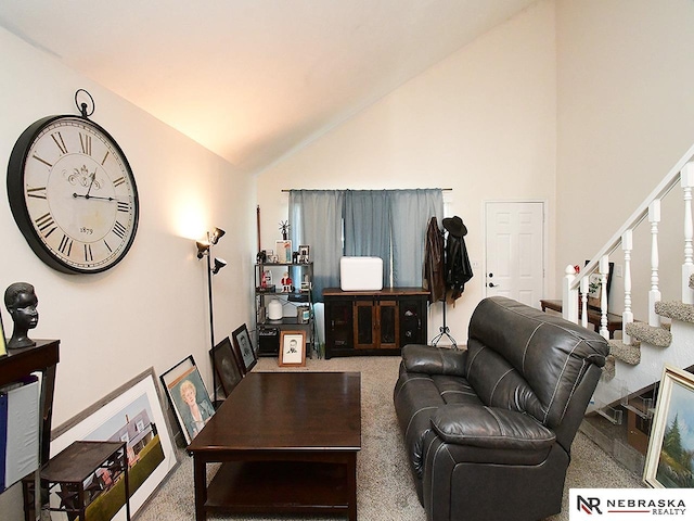 carpeted living area with stairway and high vaulted ceiling