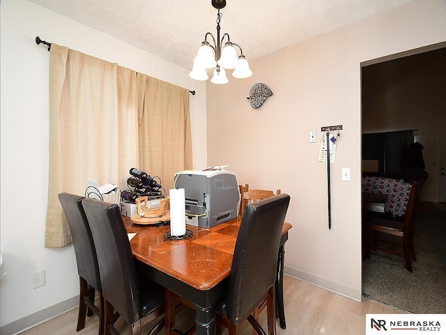 dining room featuring baseboards, a textured ceiling, an inviting chandelier, and light wood finished floors