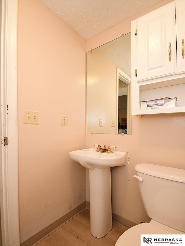 bathroom featuring baseboards, toilet, wood finished floors, and a textured ceiling