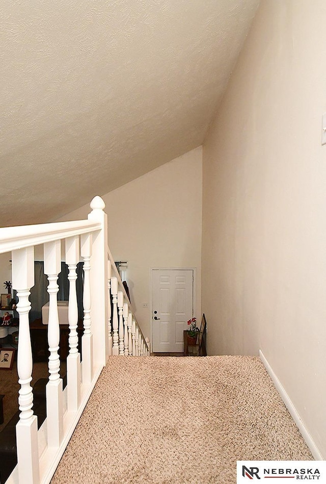 stairs with baseboards, lofted ceiling, and a textured ceiling