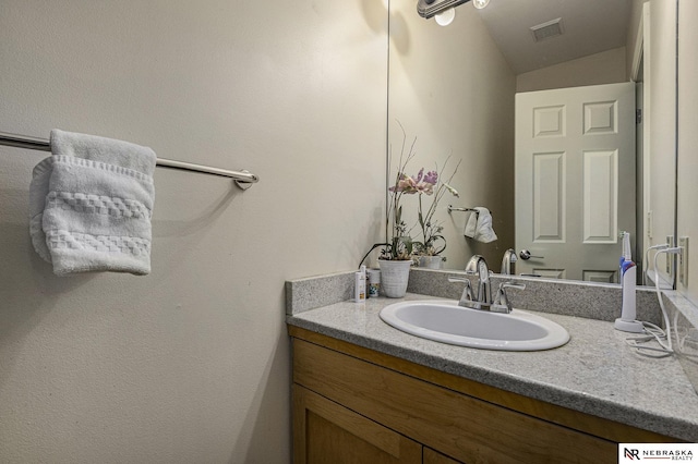 bathroom with visible vents, lofted ceiling, and vanity