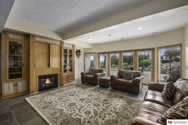 living room with recessed lighting, a textured ceiling, and a large fireplace