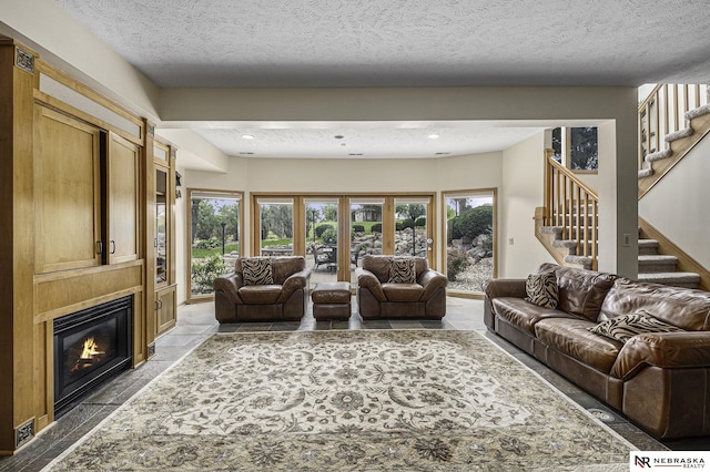 living area featuring a textured ceiling, stairway, plenty of natural light, and a large fireplace