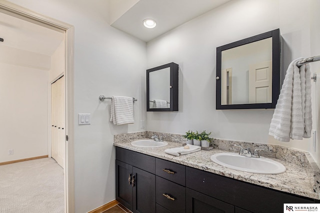 bathroom featuring double vanity, baseboards, and a sink