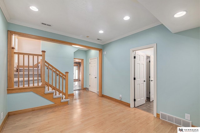 interior space with visible vents, ornamental molding, stairway, and wood finished floors