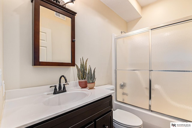 bathroom featuring shower / bath combination with glass door, visible vents, toilet, and vanity