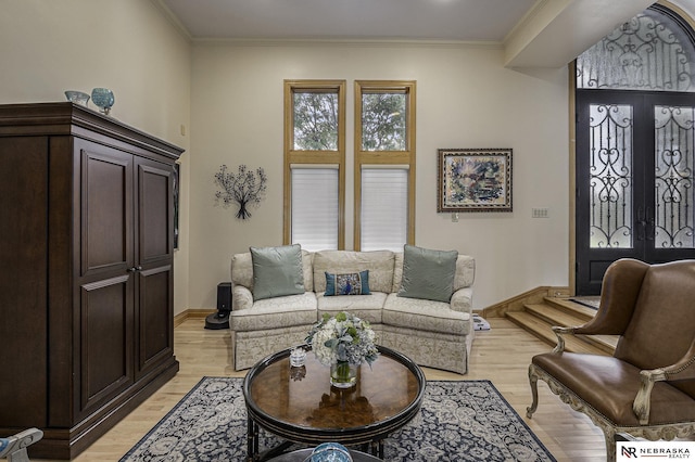 living area featuring french doors, baseboards, light wood-style floors, and ornamental molding