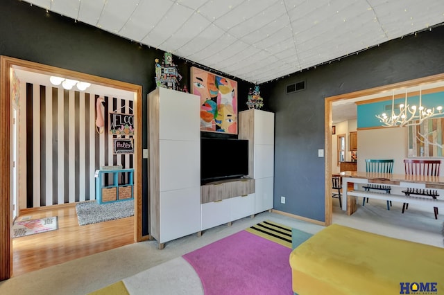 living area featuring visible vents, a notable chandelier, and carpet flooring