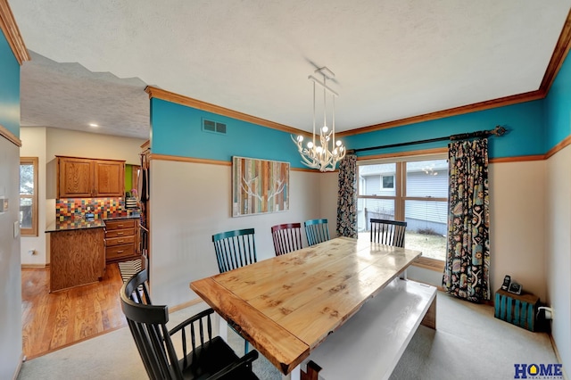 dining area featuring visible vents, baseboards, crown molding, a notable chandelier, and light colored carpet