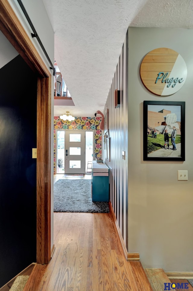 hall with a textured ceiling and wood finished floors