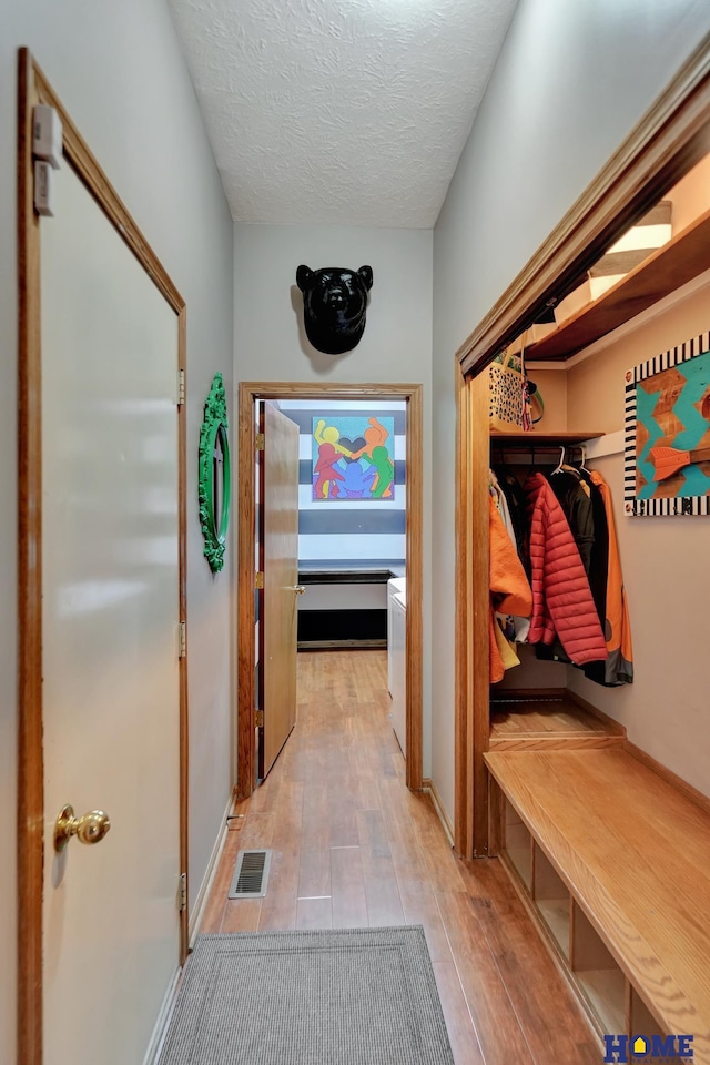 mudroom featuring visible vents, a textured ceiling, and light wood-type flooring