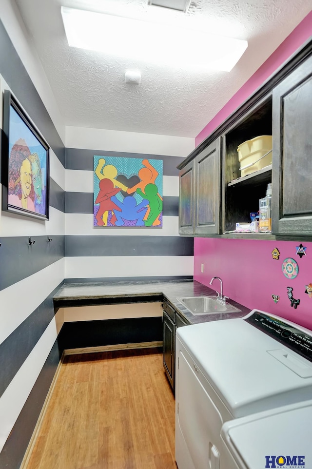 kitchen with washer and dryer, a textured ceiling, light wood finished floors, and a sink