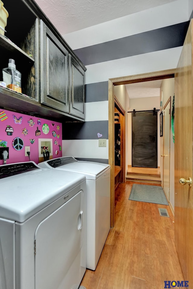 washroom with cabinet space, visible vents, washer and dryer, and light wood-style flooring