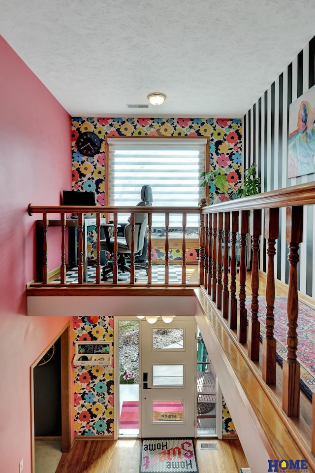 interior space featuring wallpapered walls, wood finished floors, visible vents, and a textured ceiling