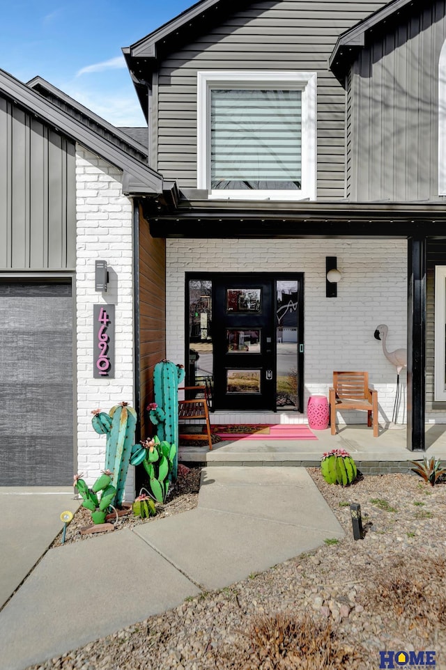 property entrance featuring a garage, brick siding, and a porch