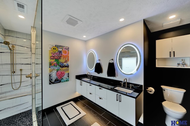 full bath featuring visible vents, toilet, a stall shower, a textured ceiling, and a sink