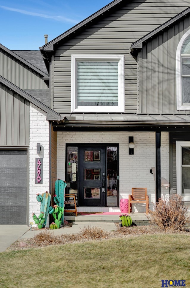 view of exterior entry featuring an attached garage and brick siding