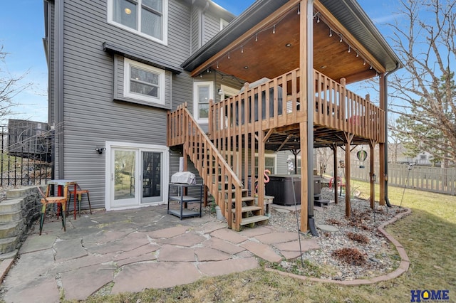 exterior space with stairs, a wooden deck, fence, and a hot tub