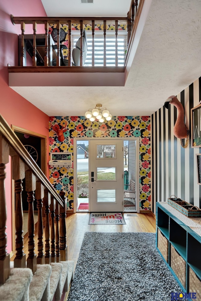 entryway featuring stairway, a textured ceiling, visible vents, and wood finished floors